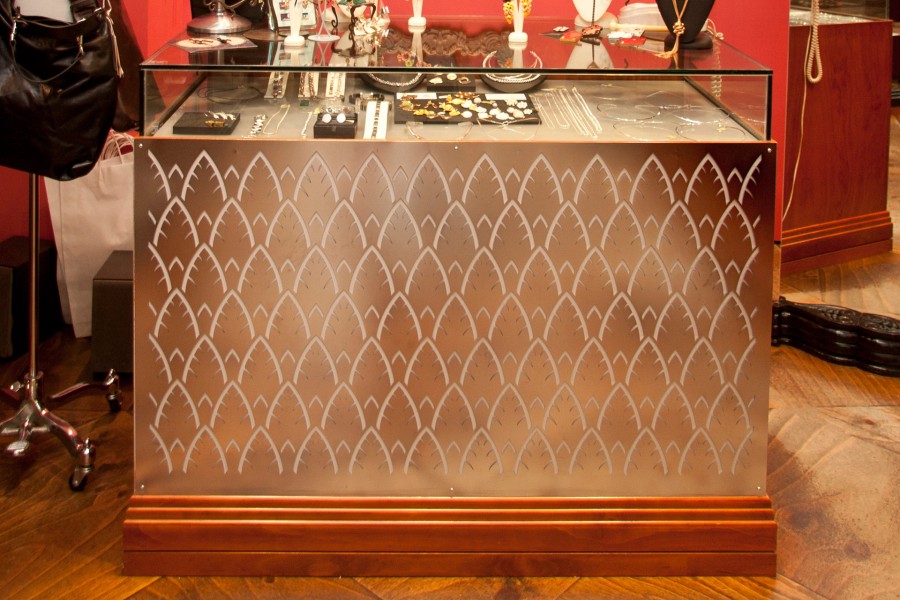 Bespoke glass-top jewellery display counter with decorative laser-cut metal front by Woodcraft Cabinets